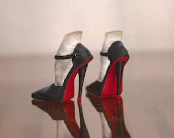 May include: A pair of black high-heeled shoes with red soles. The shoes have a strap across the ankle and a pointed toe.