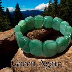 Puede incluir: Un brazalete de ágata verde con cuentas rectangulares. El brazalete se muestra sobre una roca con un fondo escénico de montañas y árboles. El texto "Green Agate" está en la parte inferior de la imagen.