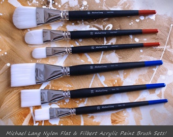 May include: Set of six Michael Lang nylon flat and filbert paint brushes. The brushes are white with black handles and blue or red accents. The brushes are arranged in order of size, with the largest brush at the top and the smallest brush at the bottom.