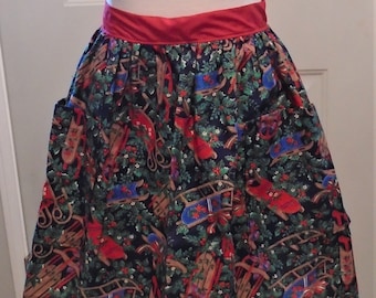 May include: A Christmas-themed apron with a dark blue background, featuring a pattern of red, blue, and brown sleds, holly, and berries. The apron has a red waistband and two pockets.