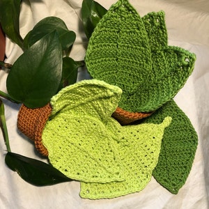 May include: A crocheted plant pot with green leaves. The pot is made of brown yarn and the leaves are made of green yarn.
