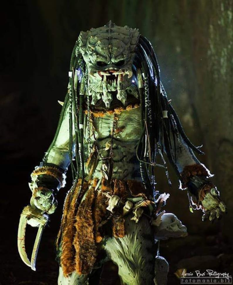 Pu&ograve; includere: Un costume da Predator verde e nero con una maschera dettagliata, dreadlocks e un perizoma di pelliccia. Il costume &egrave; accessoriato con dettagli in osso e metallo.