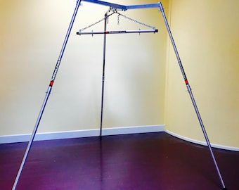 May include: A silver metal stand with three legs and a horizontal bar. The stand is used for hanging items from a chain. The stand has the text "Teltrus.com" printed on the legs.