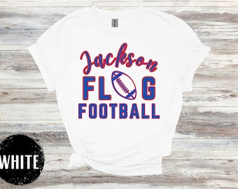 May include: White t-shirt with red and blue text that says "Jackson FLG FOOTBALL" with a blue and white football graphic.