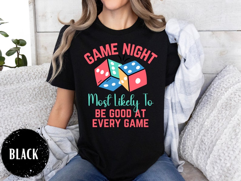May include: Black t-shirt with the text "Game Night Most Likely To Be Good At Every Game" and a graphic of colorful dice.