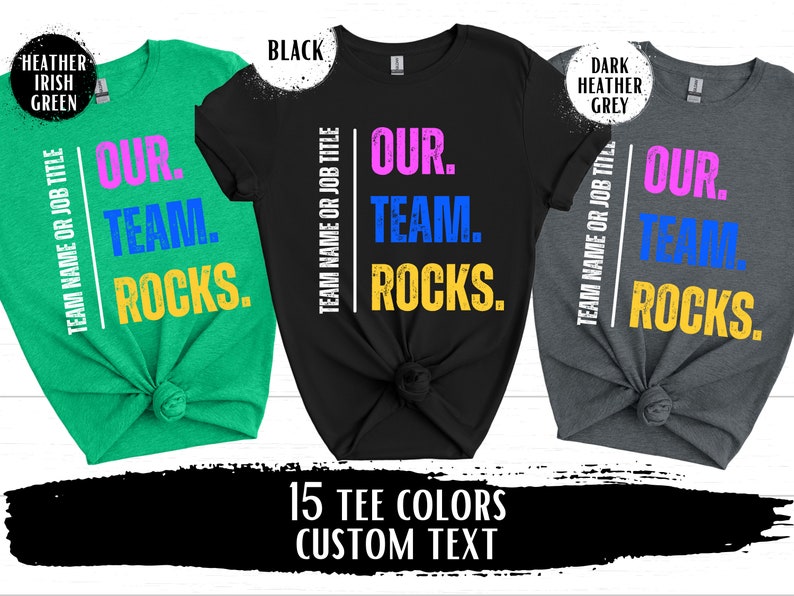 May include: Three t-shirts in different colors with the text "Our Team Rocks." The text is in pink, blue, and yellow on a white background. The t-shirts are in heather Irish green, black, and dark heather grey.