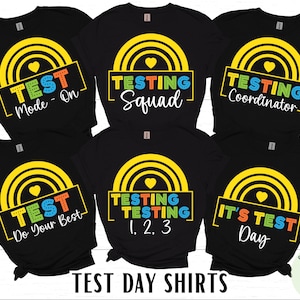 May include: Black t-shirts with colorful text and graphics for test day. Designs include "Test Mode - On", "Testing Squad", "Testing Coordinator", "Do Your Best", "Testing 1, 2, 3", and "It's Test Day".