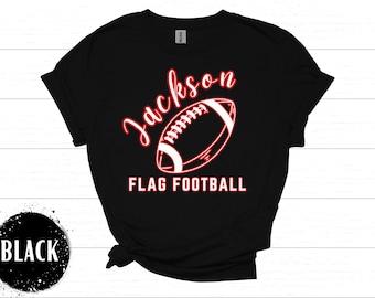 May include: Black t-shirt with the name "Jackson" in red script above a red and white football graphic. Below the football, the text "FLAG FOOTBALL" is displayed in red block letters. A black circle with the word "BLACK" is in the lower left.