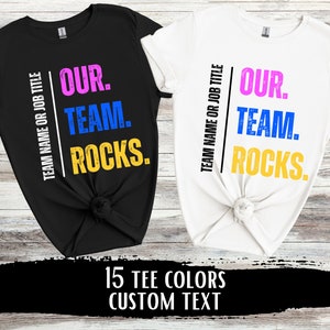 May include: Two t-shirts, one black and one white, with the text "TEAM NAME OR JOB TITLE OUR. TEAM. ROCKS." printed on them. The text is in different colors, including pink, blue, and yellow.