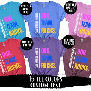 May include: A collage of 10 t-shirts in different colors, each featuring the text "OUR. TEAM. ROCKS." in various colors. The text is centered on the shirts and is surrounded by a white border. The shirts are arranged in a grid pattern, with the colors alternating between light and dark. The text "15 TEE COLORS CUSTOM TEXT" is displayed at the bottom of the image.