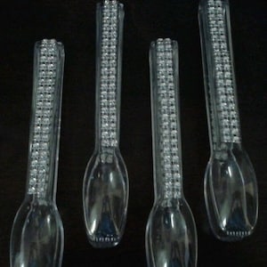 May include: Four clear plastic spoons with a decorative design of rhinestones on the handle.
