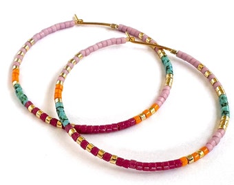May include: A pair of gold hoop earrings with pink, orange, turquoise, and gold beads.