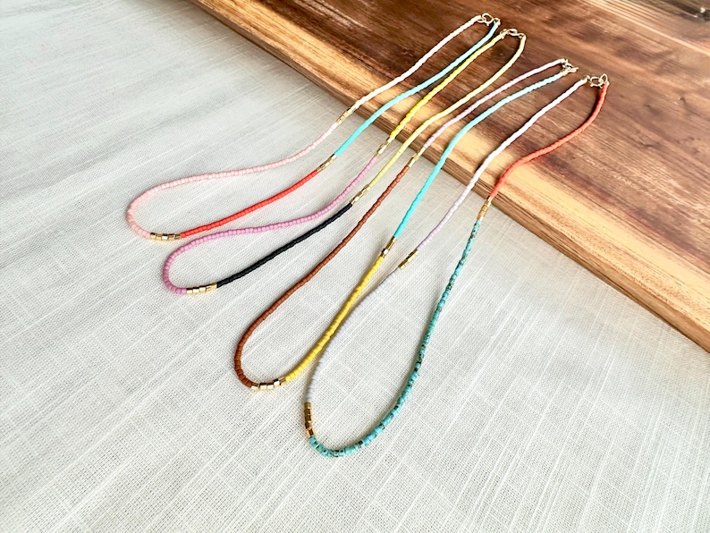 Thin beaded necklaces draped over a wooden board