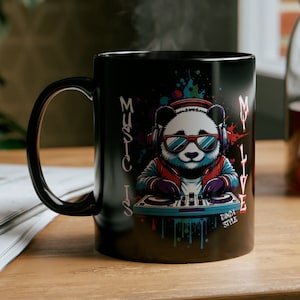 May include: Black ceramic mug with a colorful graphic of a panda wearing headphones and sunglasses, mixing music on a DJ mixer. The text "MUSIC IS MY LIFE" is printed on the mug. The text "PANDA STYLE" is printed below the panda.
