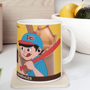 May include: White ceramic mug featuring a cartoon illustration of a boy in a baseball cap holding a red bat. The mug has a yellow background with a chocolate drink graphic and the word "MINERALES".