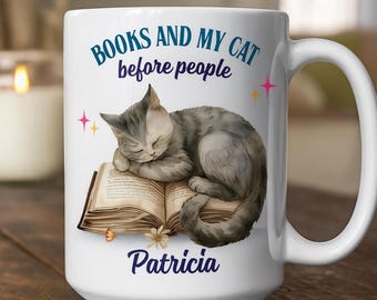 May include: White ceramic mug featuring a sleeping gray tabby cat on an open book. The mug has the text "BOOKS AND MY CAT before people" and the name "Patricia" in a script font. Pink and yellow star accents are also present.