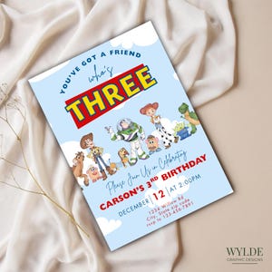 Op de afbeelding: Een lichtblauwe verjaardagsuitnodiging met personages uit de film Toy Story. De uitnodiging luidt "You've got a friend who's THREE" met de naam van het kind en feestdetails. De uitnodiging is versierd met wolken en de tekst "Please Join Us in Celebrating".