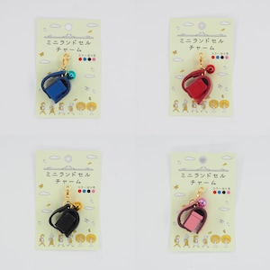 May include: Four miniature school bag charms with a gold chain and bell. The bags are blue, red, black, and pink. Each charm is displayed on a white card with Japanese text that reads "Mini Landsel Charm".