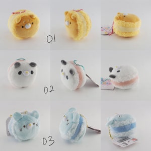 May include: Nine plush keychain charms shaped like macarons with different animal faces. The macarons are yellow, white, and blue with pink, white, and blue frosting. The animals include a bear, panda, and cat.