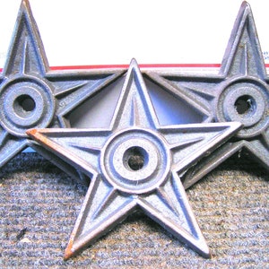 May include: Three silver-colored cast iron star-shaped wall mounts with a circular hole in the center of each star.