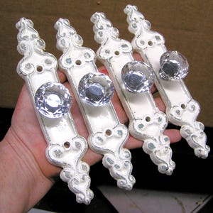 May include: Four white porcelain door knobs with ornate designs and clear glass crystal knobs.