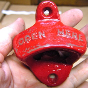 May include: Red metal bottle opener with the words "OPEN HERE" embossed on the top.