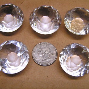 May include: Five clear glass crystal prisms with a faceted design. The prisms are round and have a slightly domed shape.