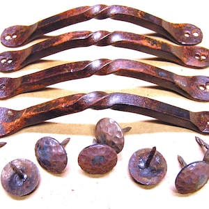 May include: Four rustic, twisted iron door pulls with a hammered finish. The pulls are arranged in a row, with the top pull slightly overlapping the one below it.  The pulls are accompanied by ten hammered iron nails.