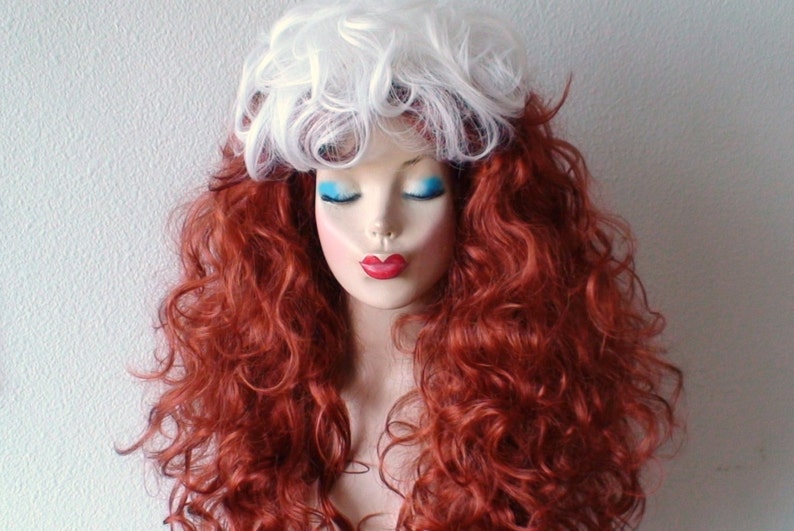 May include: A long, curly red wig with a white, curly top section. The wig is styled on a mannequin head.