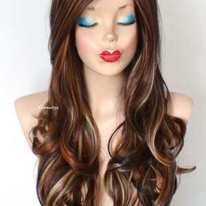 May include: Long, wavy brown wig with blonde highlights. The wig is styled with loose curls and a side part. The wig is on a mannequin head.