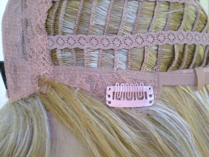 May include: The back of a blonde wig with a lace front and adjustable straps. The wig has clips to secure it to the wearer's hair.