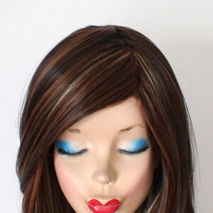 May include: A long, straight, brown wig with blonde highlights. The wig is styled with a side part and has a natural-looking finish.