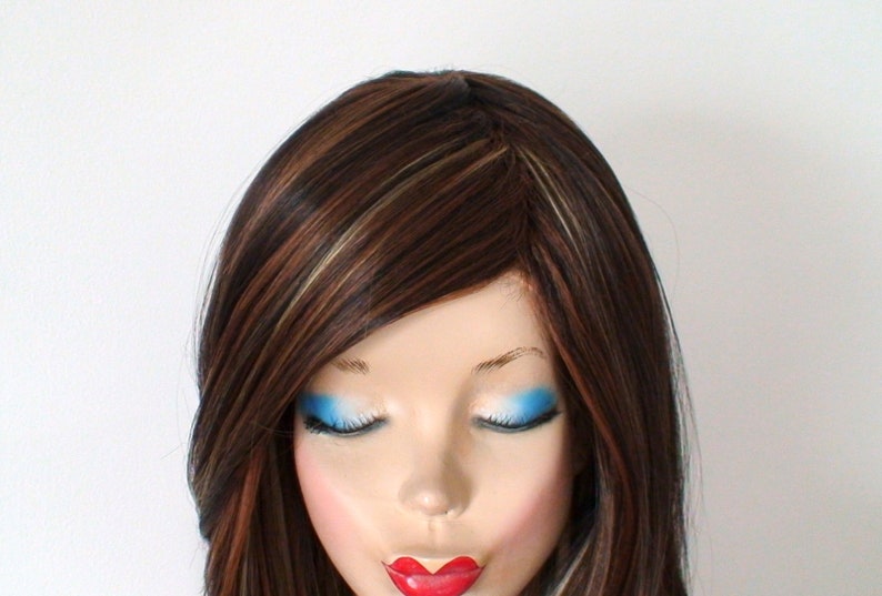 May include: A long, straight, brown wig with blonde highlights. The wig is styled with a side part and has a natural-looking finish.