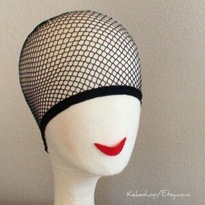 May include: Black mesh wig cap with a black elastic band. The cap is on a white mannequin head with red lips.