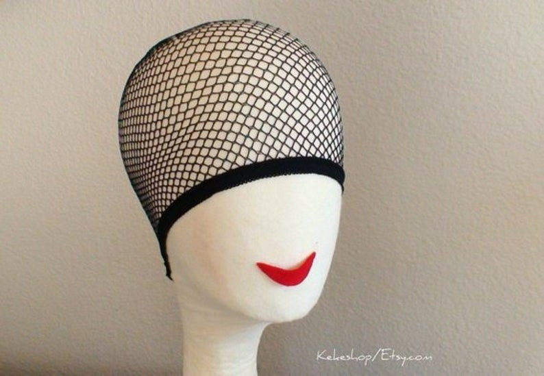 May include: Black mesh wig cap with a black elastic band. The cap is on a white mannequin head with red lips.