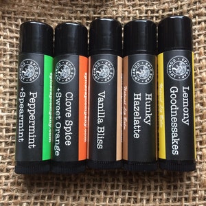 Puede incluir: Seis tubos de b&aacute;lsamo labial negros con diferentes sabores: Lemony Goodnessakes, Hunky Hazelatte, Vanilla Bliss, Clove Spice + Sweet Orange, Peppermint + Spearmint. Cada tubo tiene una etiqueta en blanco y negro con el logotipo de Epic Soap Company.