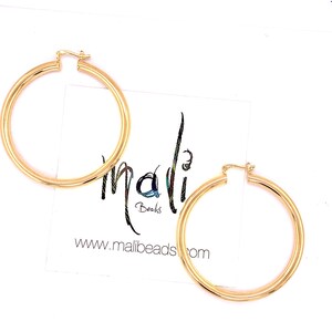May include: A pair of gold hoop earrings. The earrings are large and have a simple, classic design.