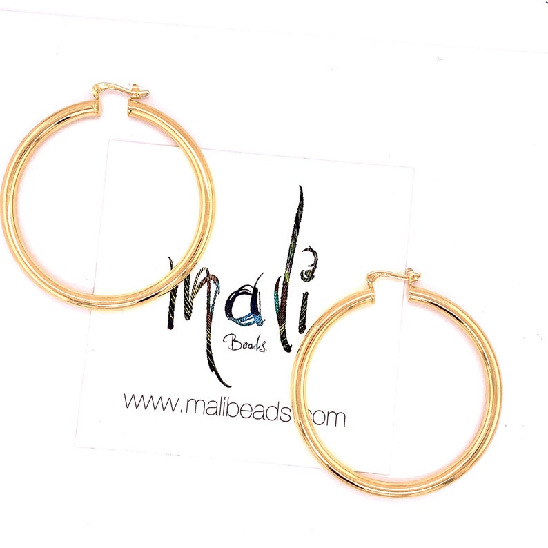 May include: A pair of gold hoop earrings. The earrings are large and have a simple, classic design.
