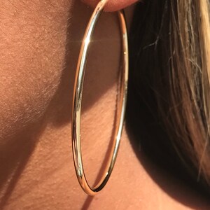 Op de afbeelding: Gouden creolen met een gladde, gepolijste afwerking. De oorbellen zijn groot en rond van vorm.