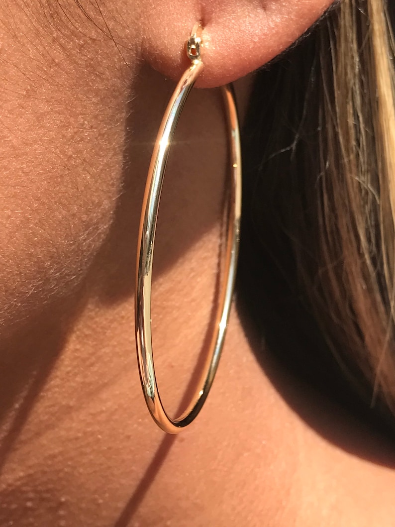 Op de afbeelding: Gouden creolen met een gladde, gepolijste afwerking. De oorbellen zijn groot en rond van vorm.