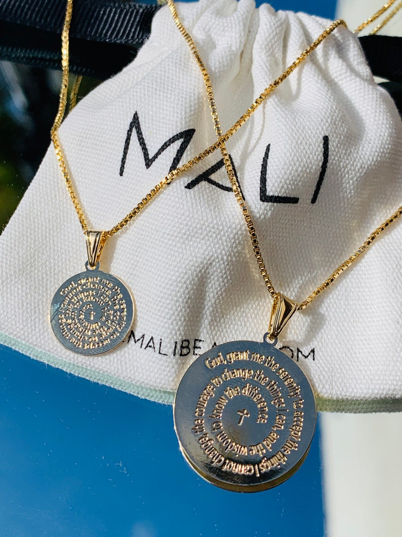 May include: Two gold necklaces with circular pendants featuring engraved text. The text on the pendants reads "God, grant me the serenity to accept the things I cannot change, courage to change the things I can, and the wisdom to know the difference." and "God, grant me the serenity to accept the things I cannot change, courage to change the things I can, and the wisdom to know the difference."
