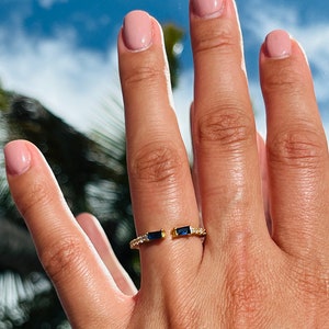 May include: A gold ring with two blue gemstones and small clear stones set in the band.
