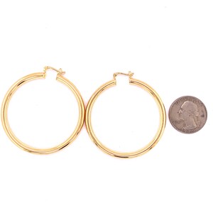 May include: A pair of gold hoop earrings. The earrings are about the size of a quarter.