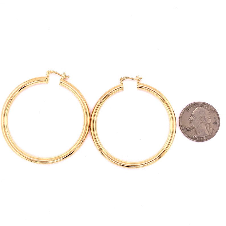 May include: A pair of gold hoop earrings. The earrings are about the size of a quarter.