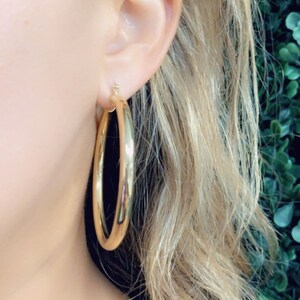 May include: Gold hoop earrings. The earrings are large and round, with a smooth, polished finish.