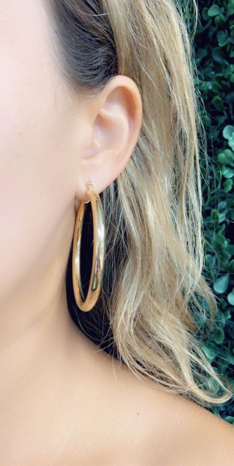 May include: Gold hoop earrings. The earrings are large and round, with a smooth, polished finish.