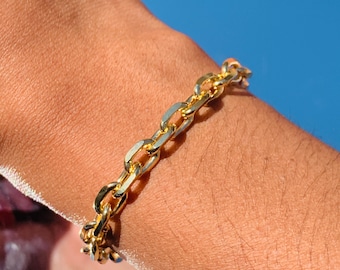 May include: A gold chain bracelet with a curb link design. The bracelet is worn on a person's wrist.