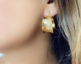 May include: Gold hoop earrings with a textured, ribbed design. The earrings are a classic style and would be a great addition to any jewelry collection.