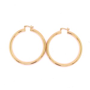May include: A pair of gold hoop earrings. The hoops are thick and have a smooth finish.