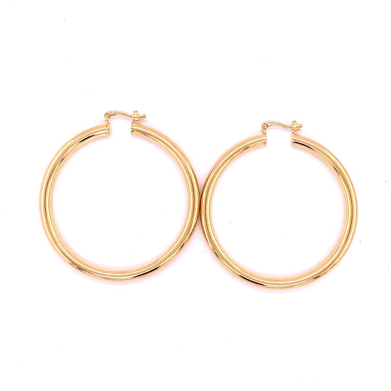 May include: A pair of gold hoop earrings. The hoops are thick and have a smooth finish.